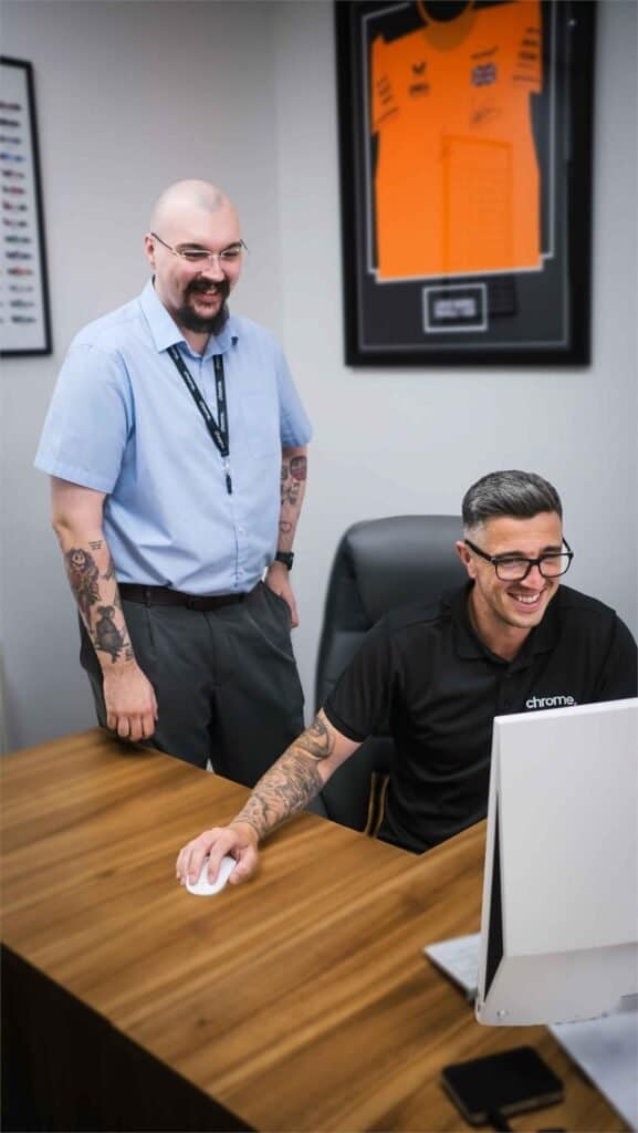 Two Chrome Telecom colleagues laughing together at a desk