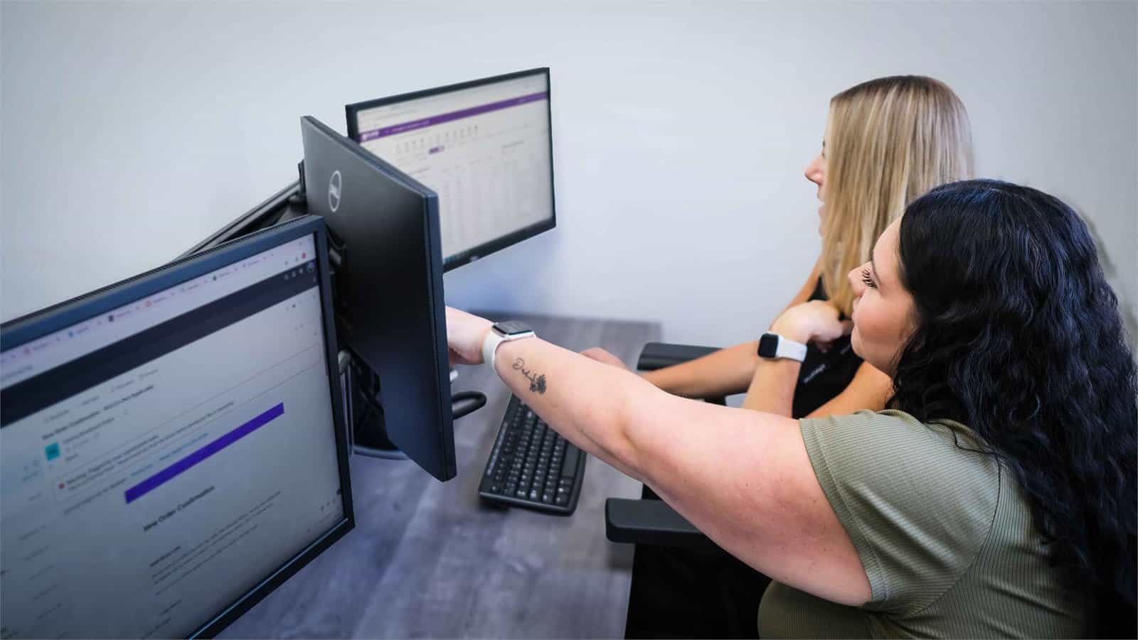 Becca helping Gemma with a query at her workstation, supporting fibre availability checks