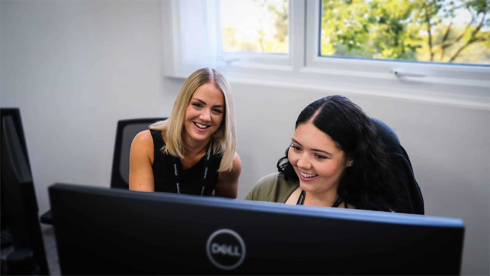 Gemma and Becca working at their desks in the Chrome Telecom office, supporting the customer portal