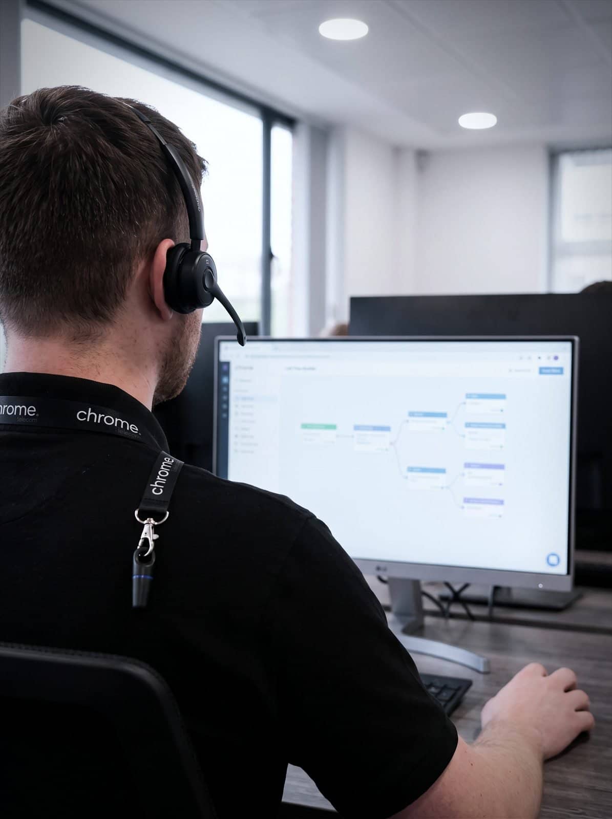 A Chrome Telecom colleague builds an automated call flow on screen while wearing a headset