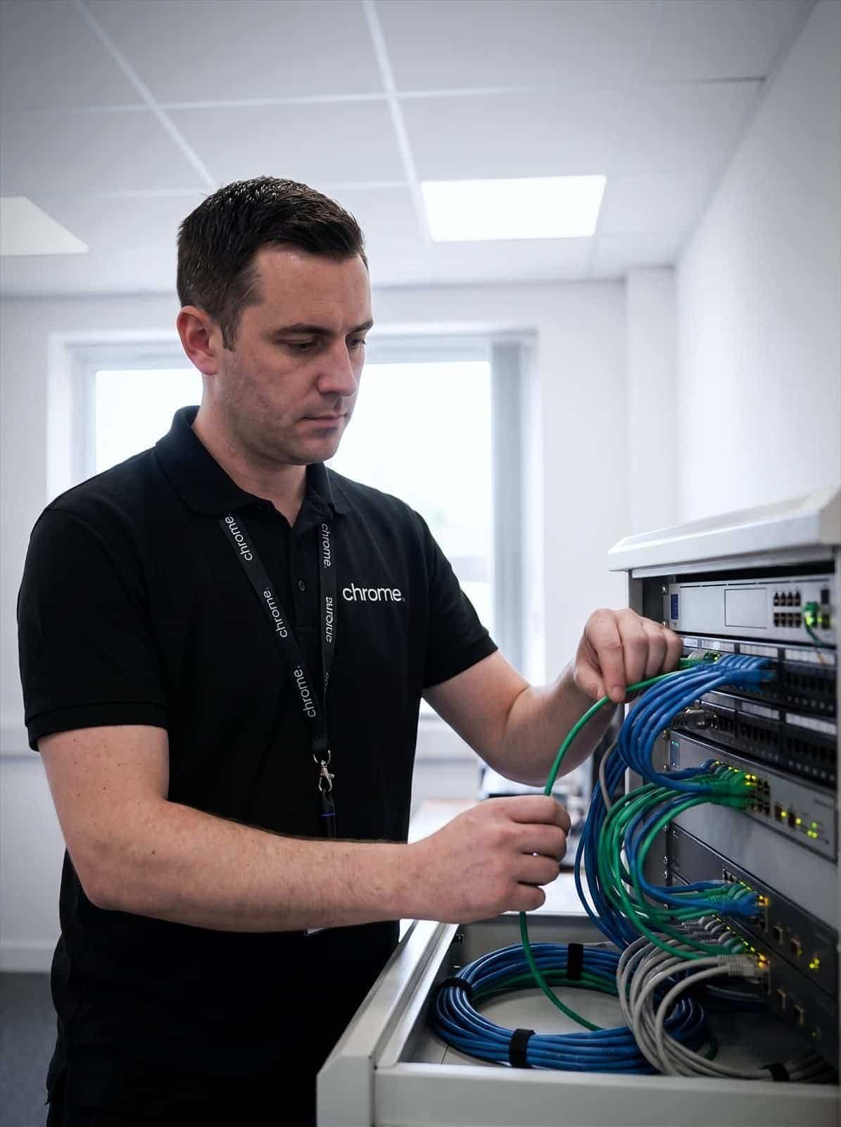 A Chrome Telecom engineer patches network cabling into a tidy comms cabinet