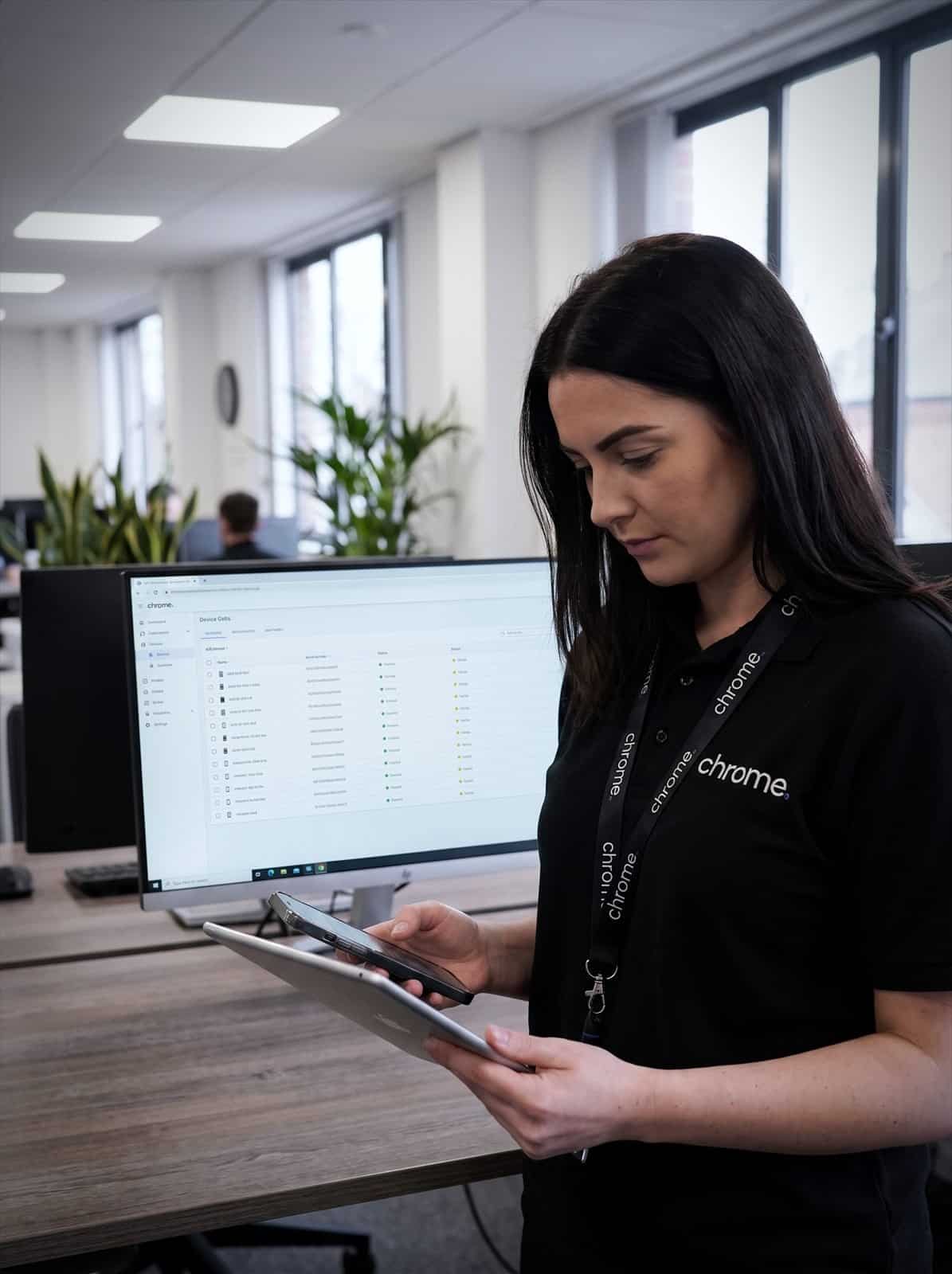 A Chrome Telecom colleague checks a tablet and phone against a managed device inventory on screen