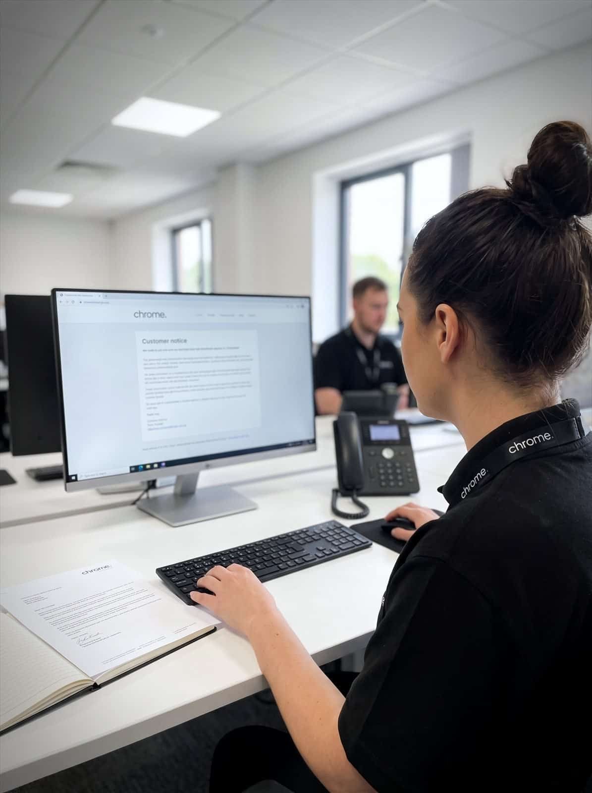 A Chrome Telecom colleague reading a customer notice at her desk