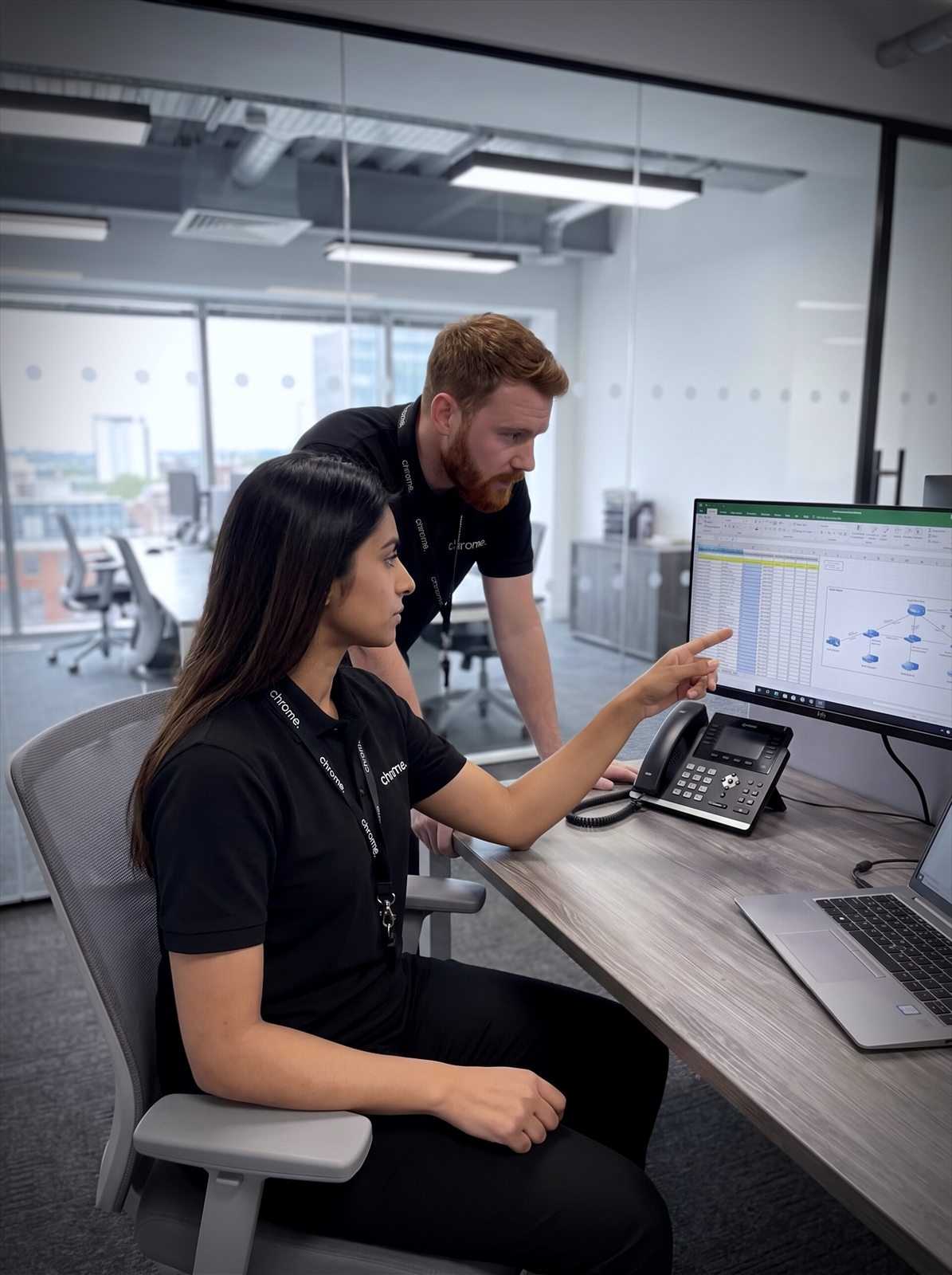 Two Chrome Telecom colleagues reviewing work together at a desk