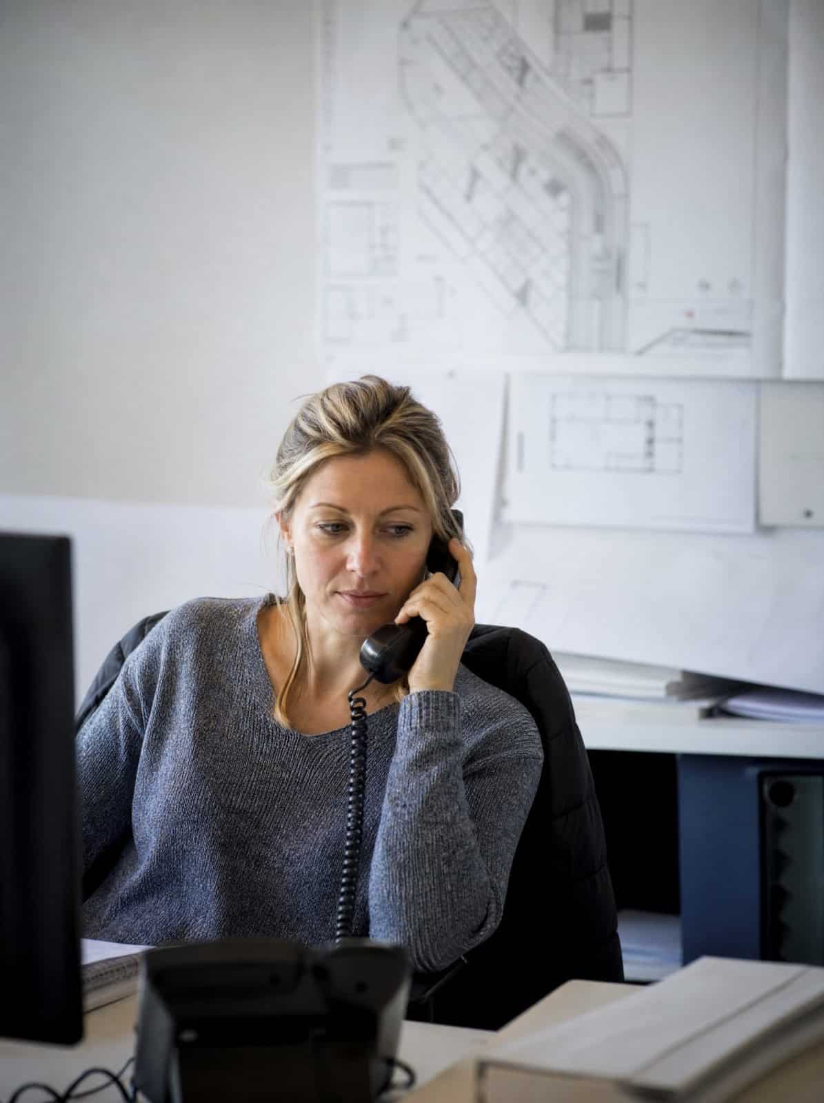 A construction company coordinator takes a call in the site office