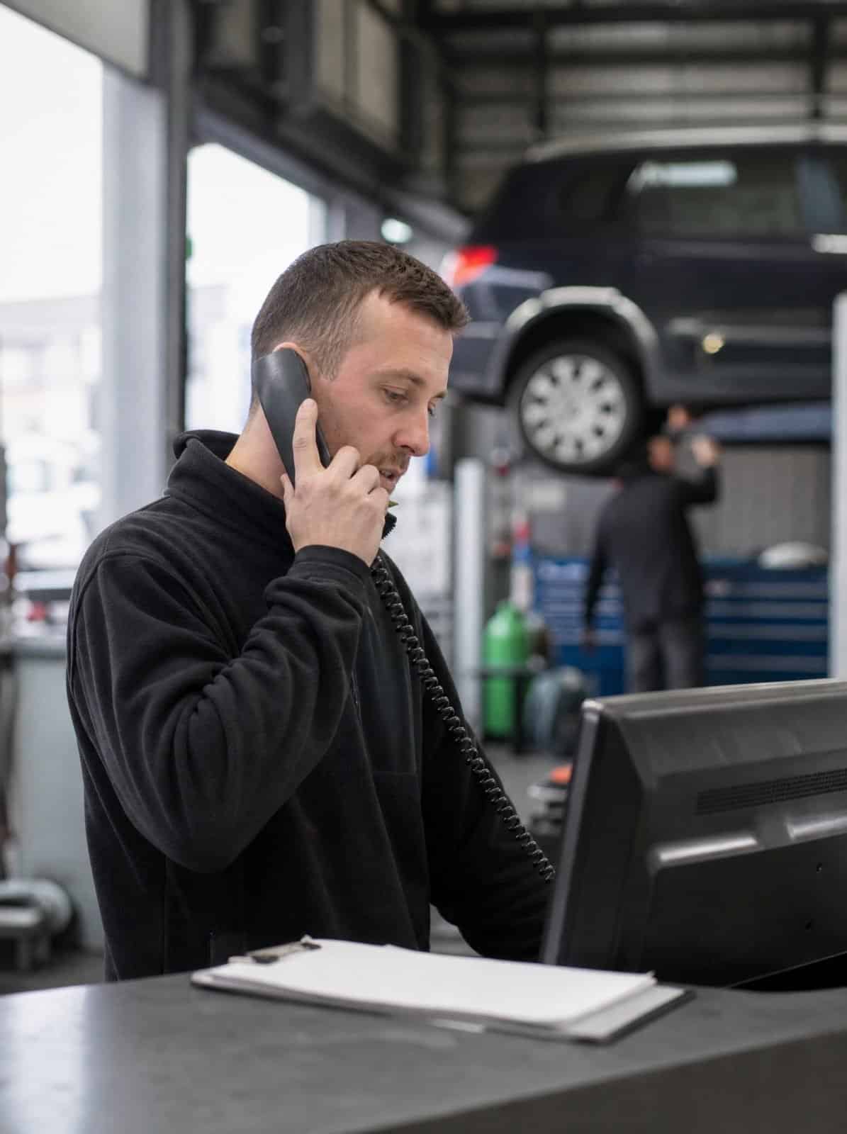 A garage service advisor takes a booking call at the service desk