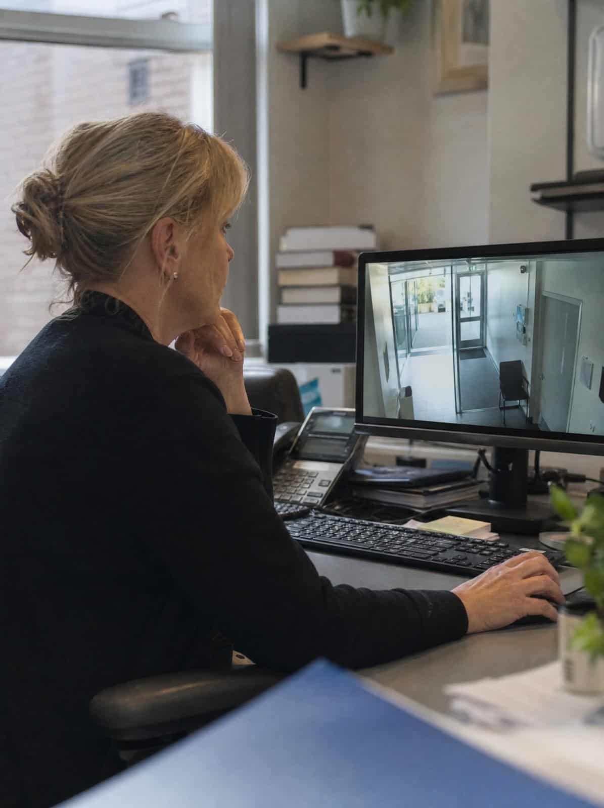 A clinic manager reviews a security camera view on a monitor