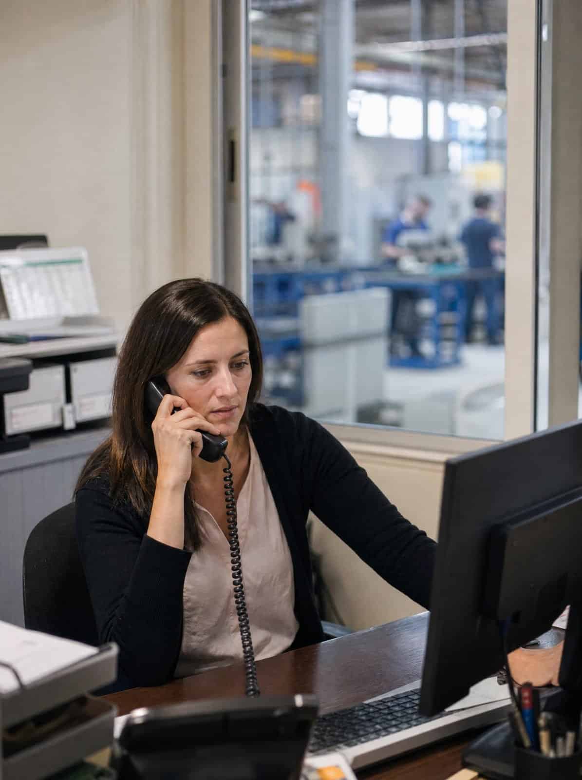An administrator answers a call in a manufacturing company office