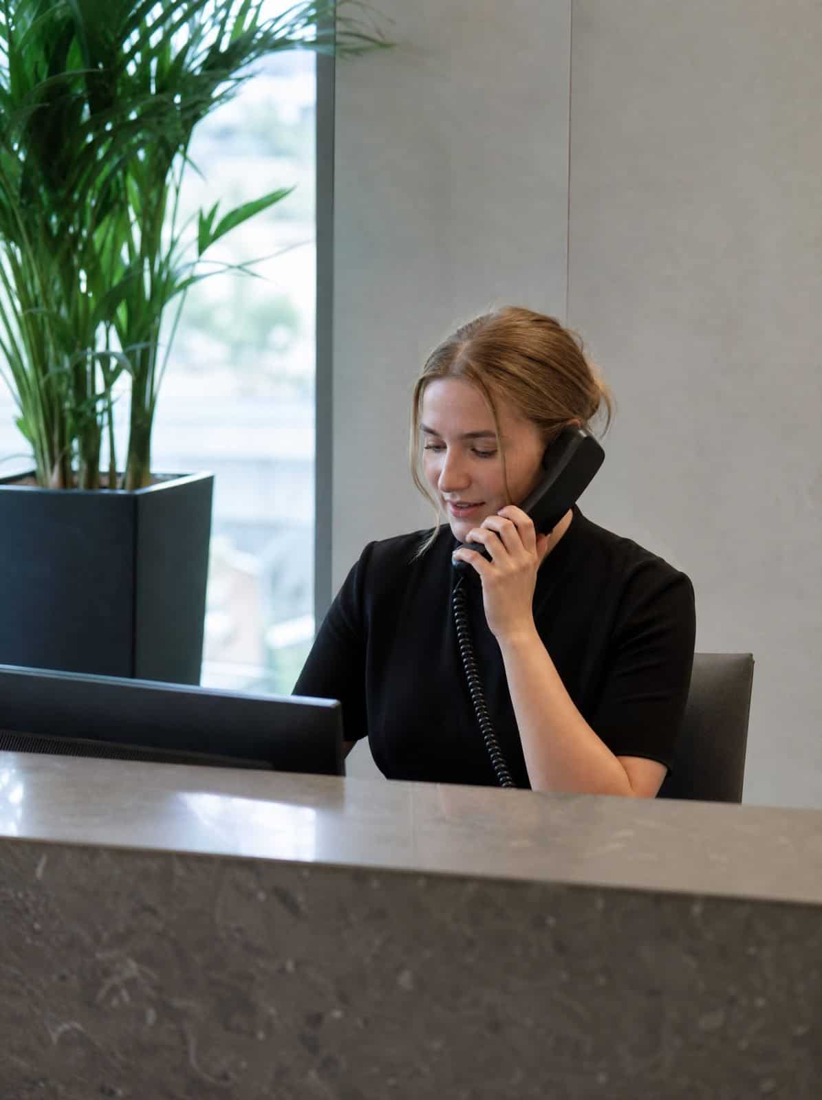 A receptionist at a professional firm answers a call at the front desk