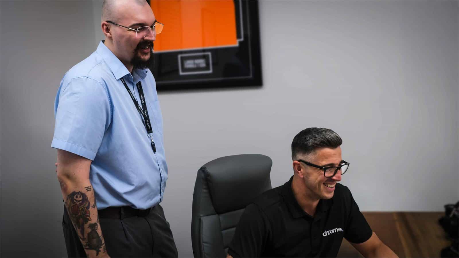 Jake and Matt sharing a laugh at their desks, supporting award-winning service