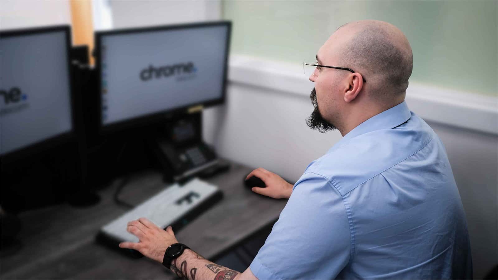 Jake working at his computer, supporting phone system features