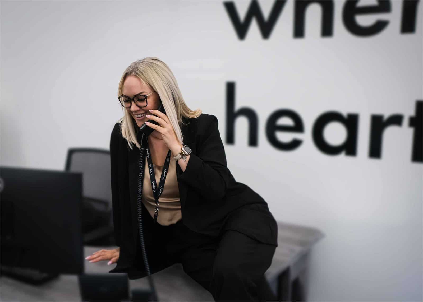 Kelly taking a call at her desk, supporting on-hold marketing