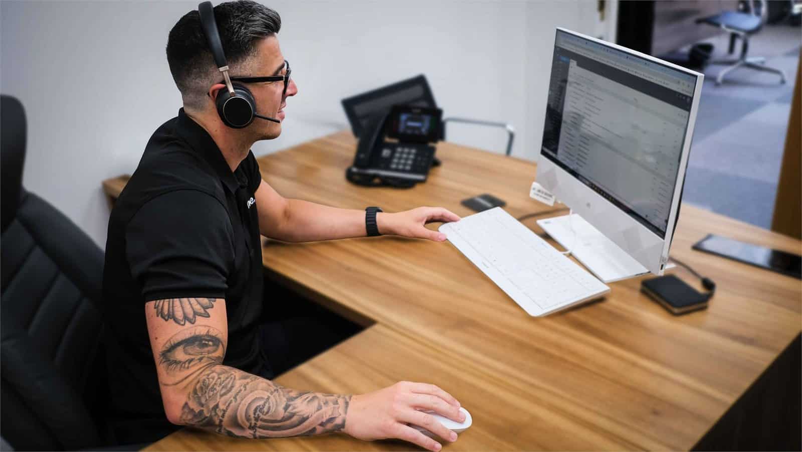 Matt working at his desk wearing a headset, supporting business communications in Hampshire