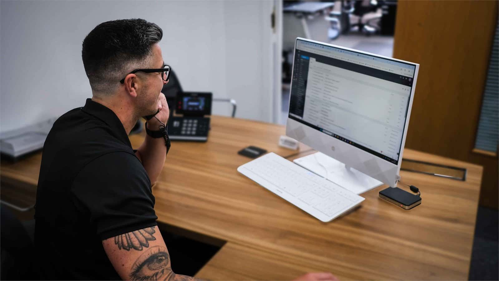Matt handling a customer call at his workstation, supporting AI transcription and meeting notes
