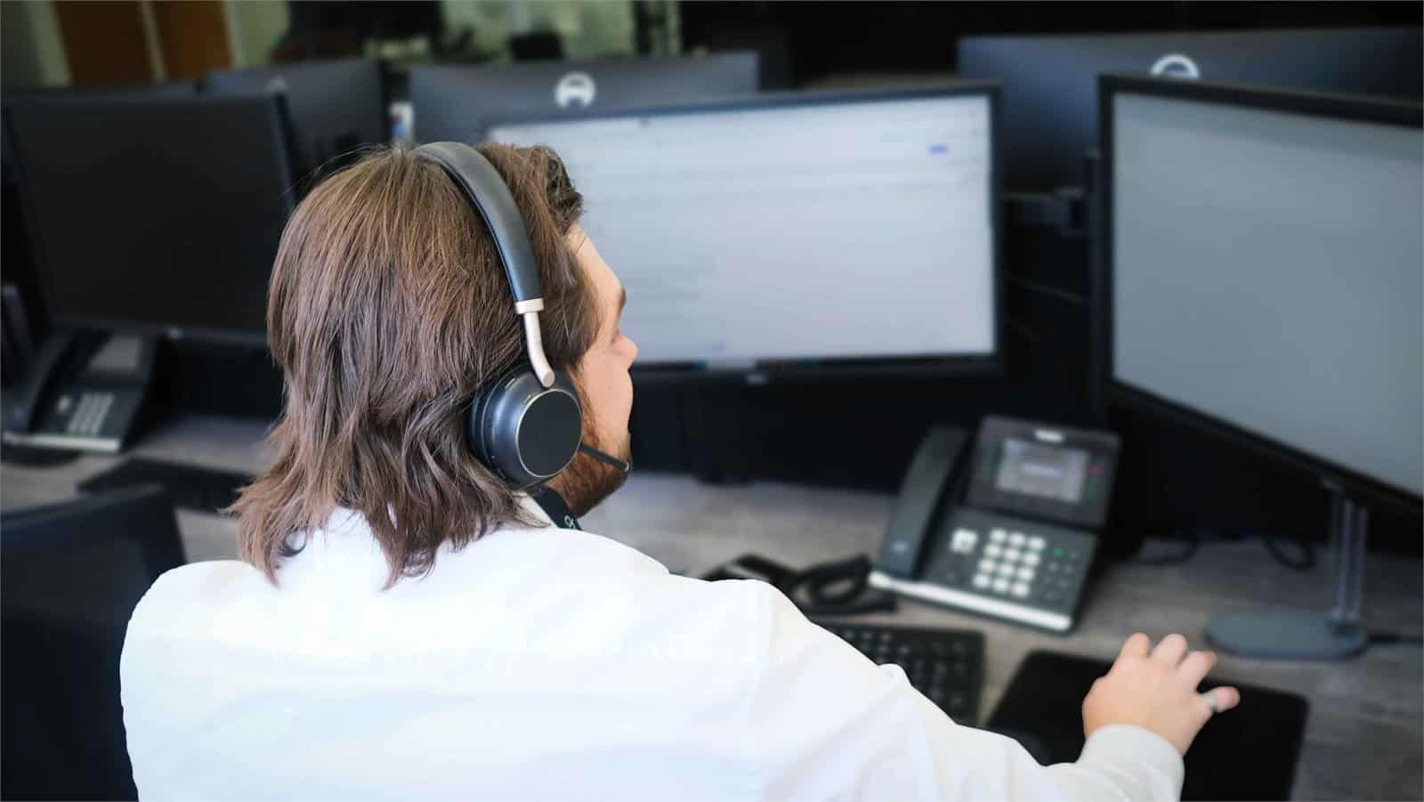 Rich taking a call on a headset at his desk, supporting 24/7 systems monitoring