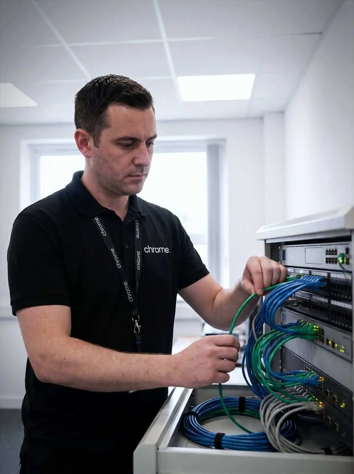 A Chrome Telecom engineer patches network cabling into a tidy comms cabinet
