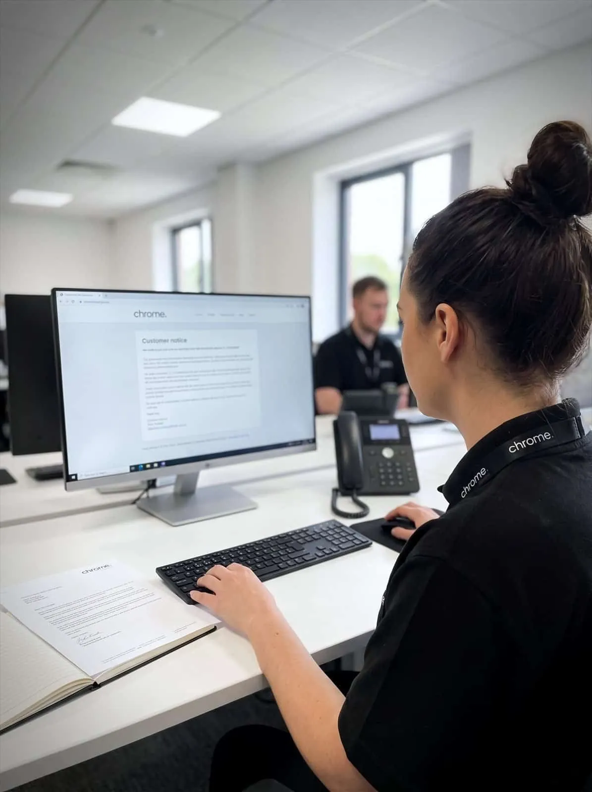 A Chrome Telecom colleague reading a customer notice at her desk