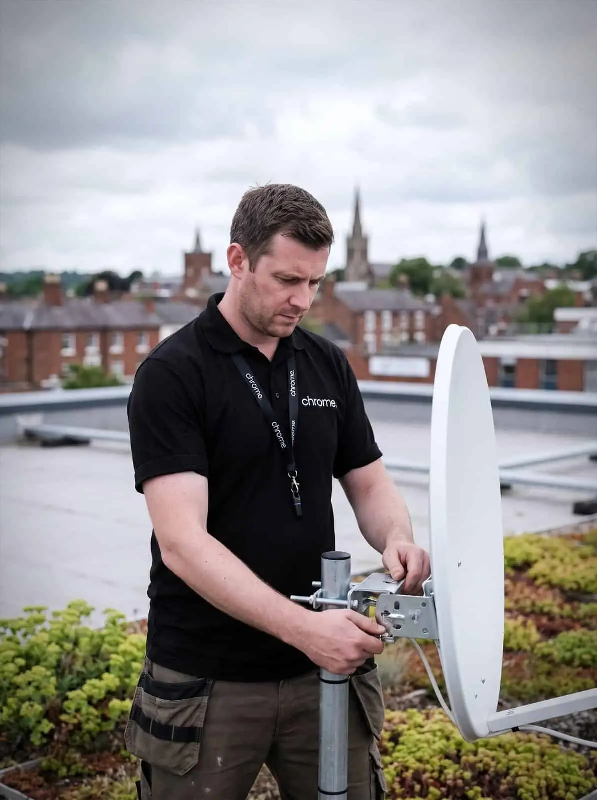 A Chrome Telecom engineer aligns a satellite internet dish on a commercial rooftop